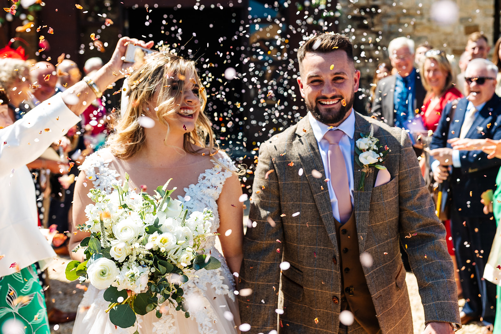 Couple leaving ceremony with confetti being thrown over them by guests 