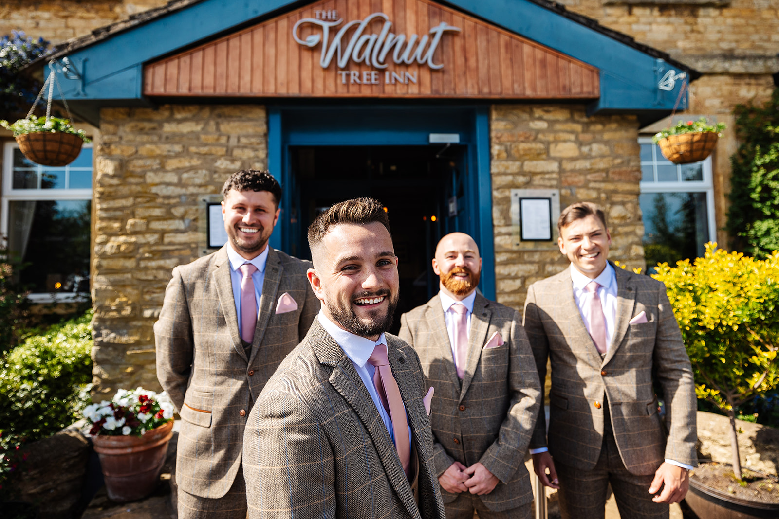 Groom and groomsmen outside The Walnut Three Inn in brown chequered suits with pink ties and pocket squares 
