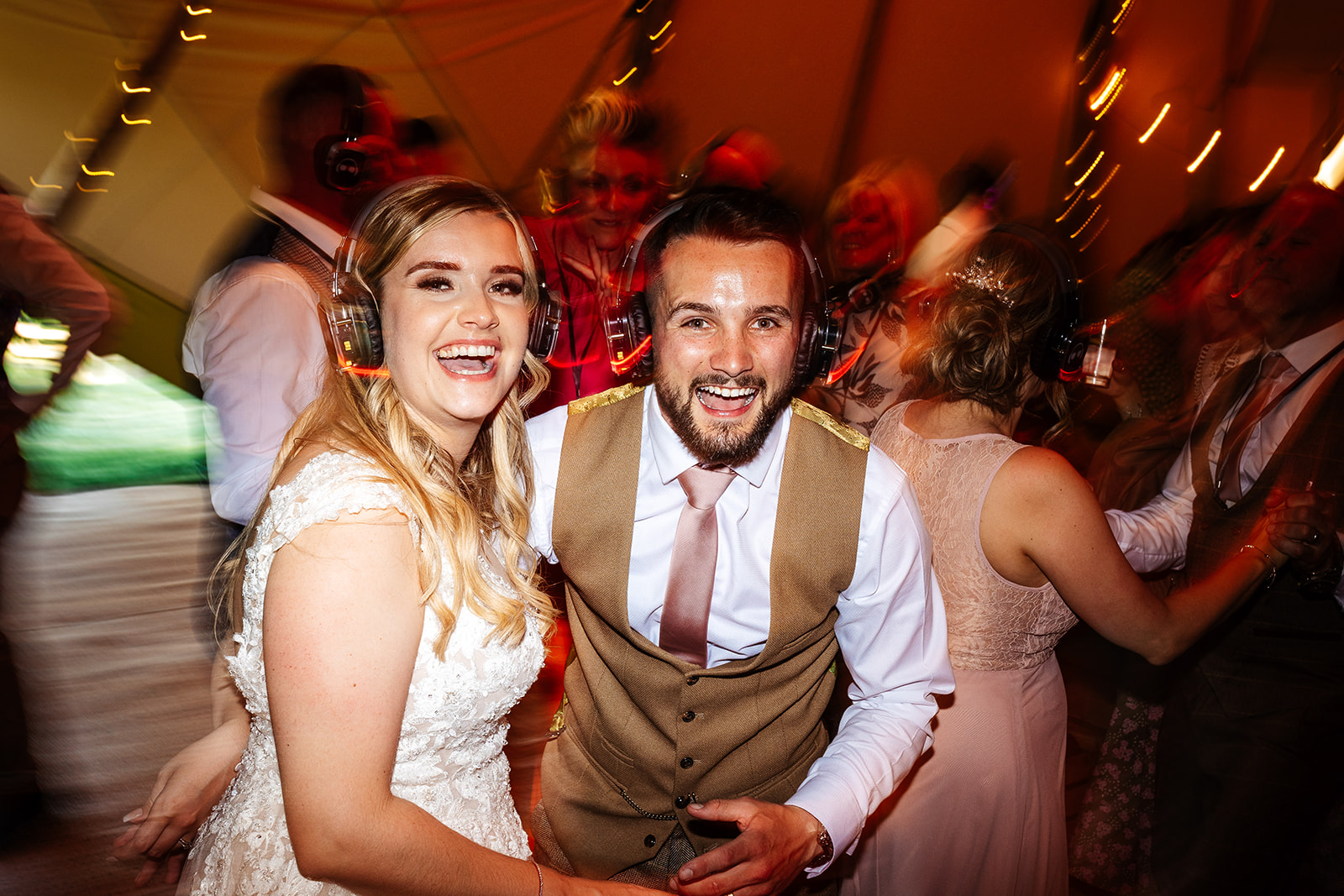 Couple with silent disco headphones on in tipi 