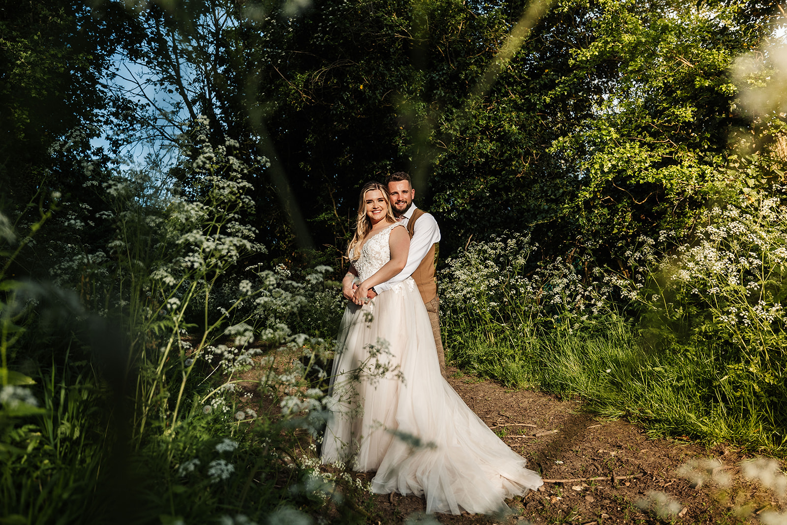 Couple in forest area surrounded by white wild flowers