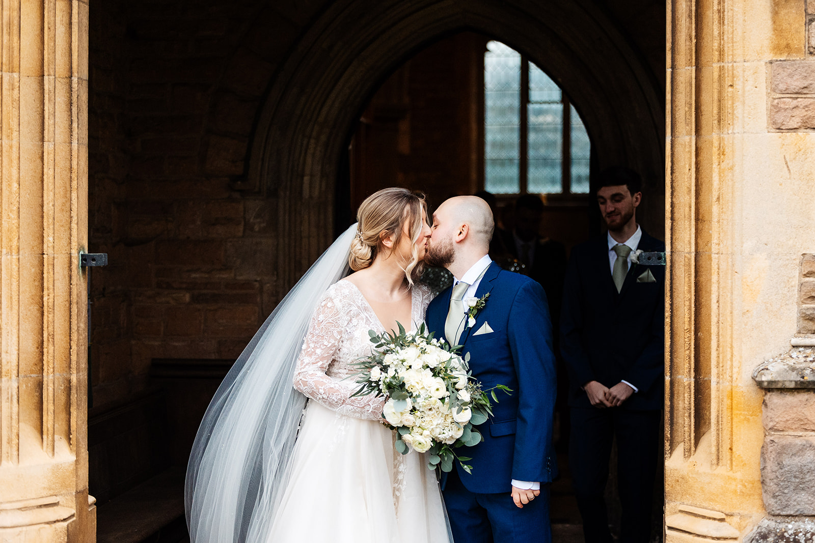 Couple walk out of church following the ceremony, pause for a kiss on the steps