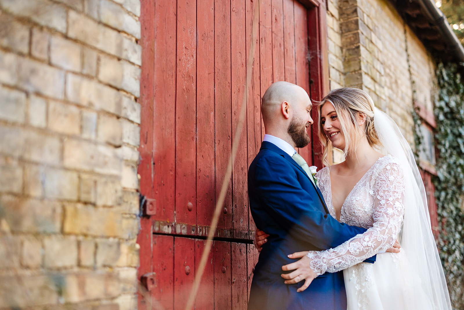 Couple embracing infront of a red door at South Farm 