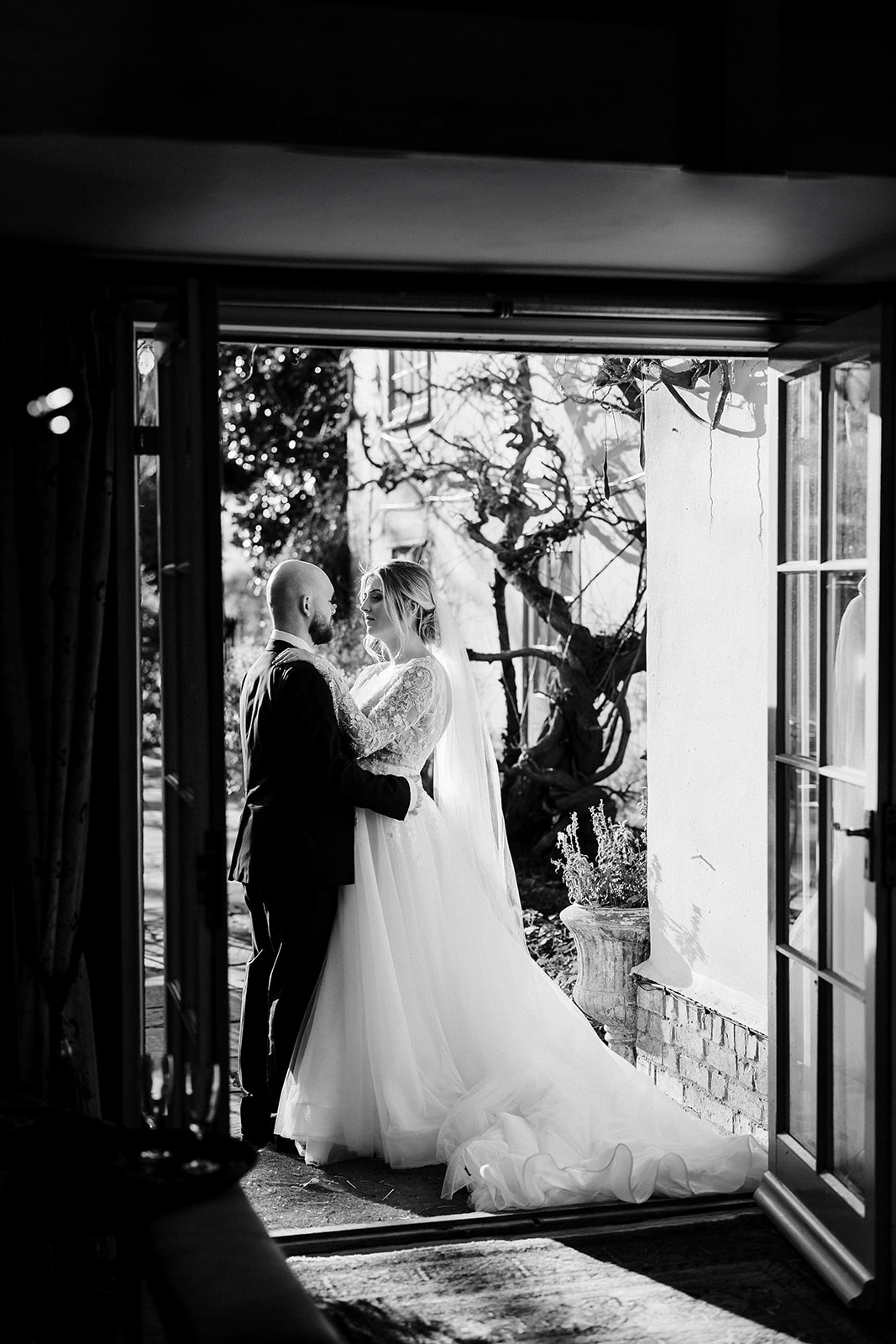 Couple share glance whilst standing in the doorway of South Farm, in black and white 