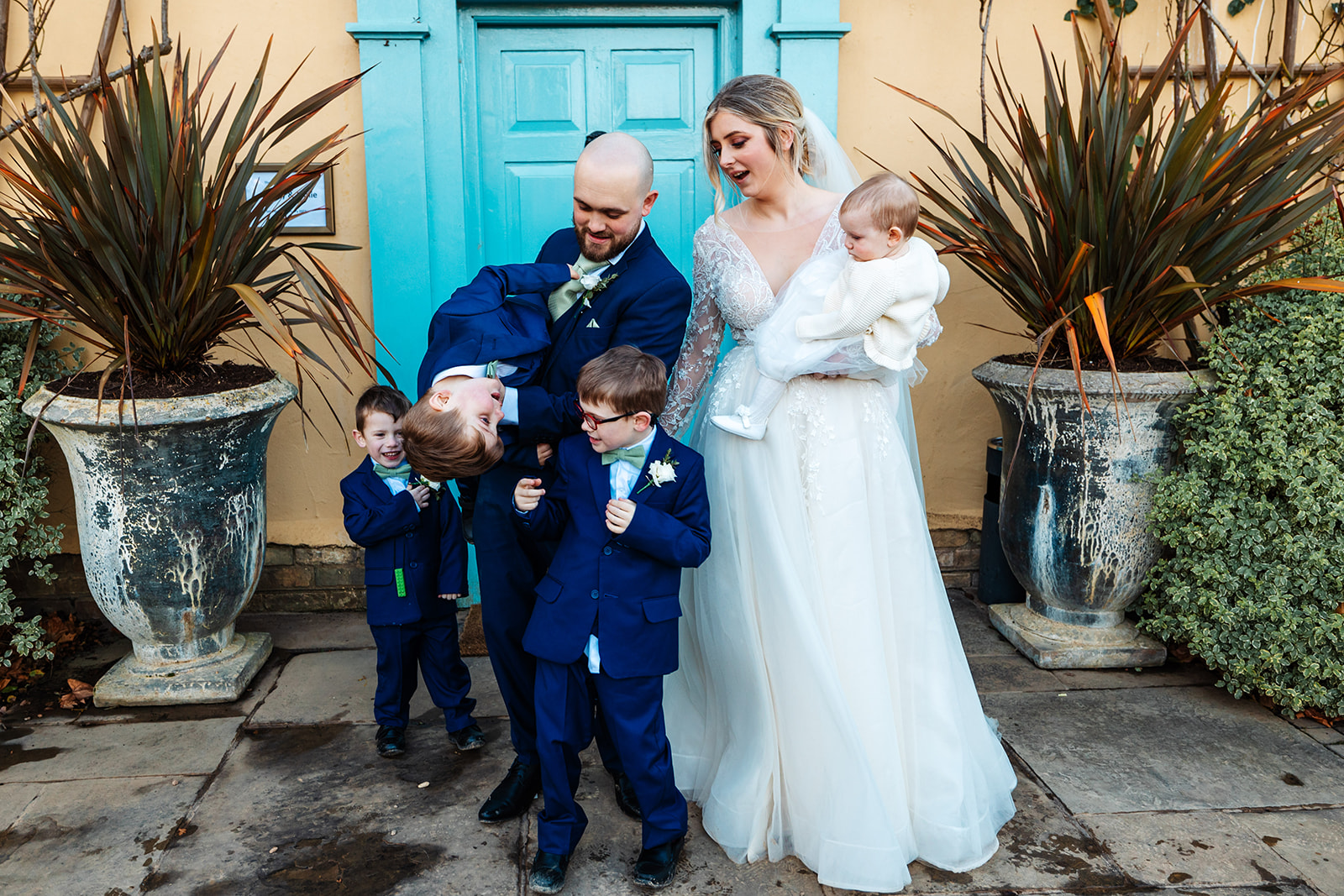 Couple with their children Infront of main house at South Farm with blue door in the background 