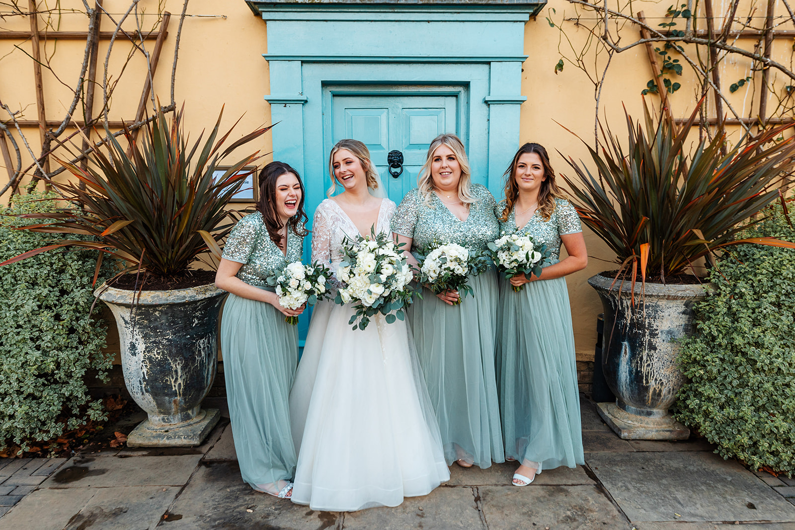Bride and bridesmaids in green sequin dresses infront of main house at south farm