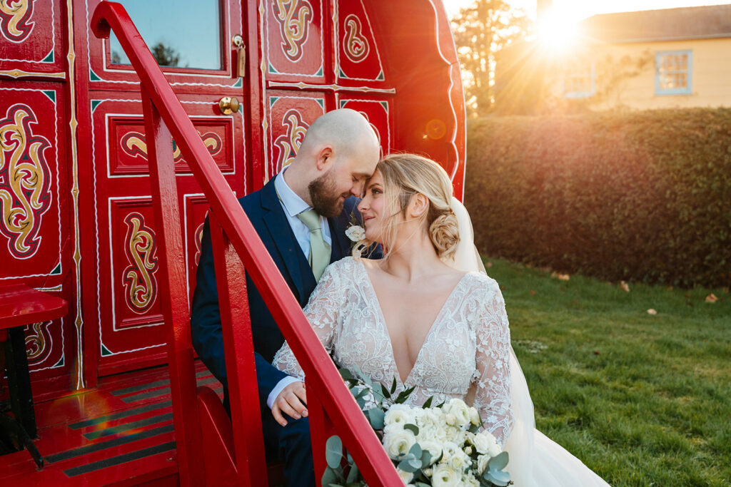 south farm romany caravans with bride and groom sat on steps with sunlight bursting behind them