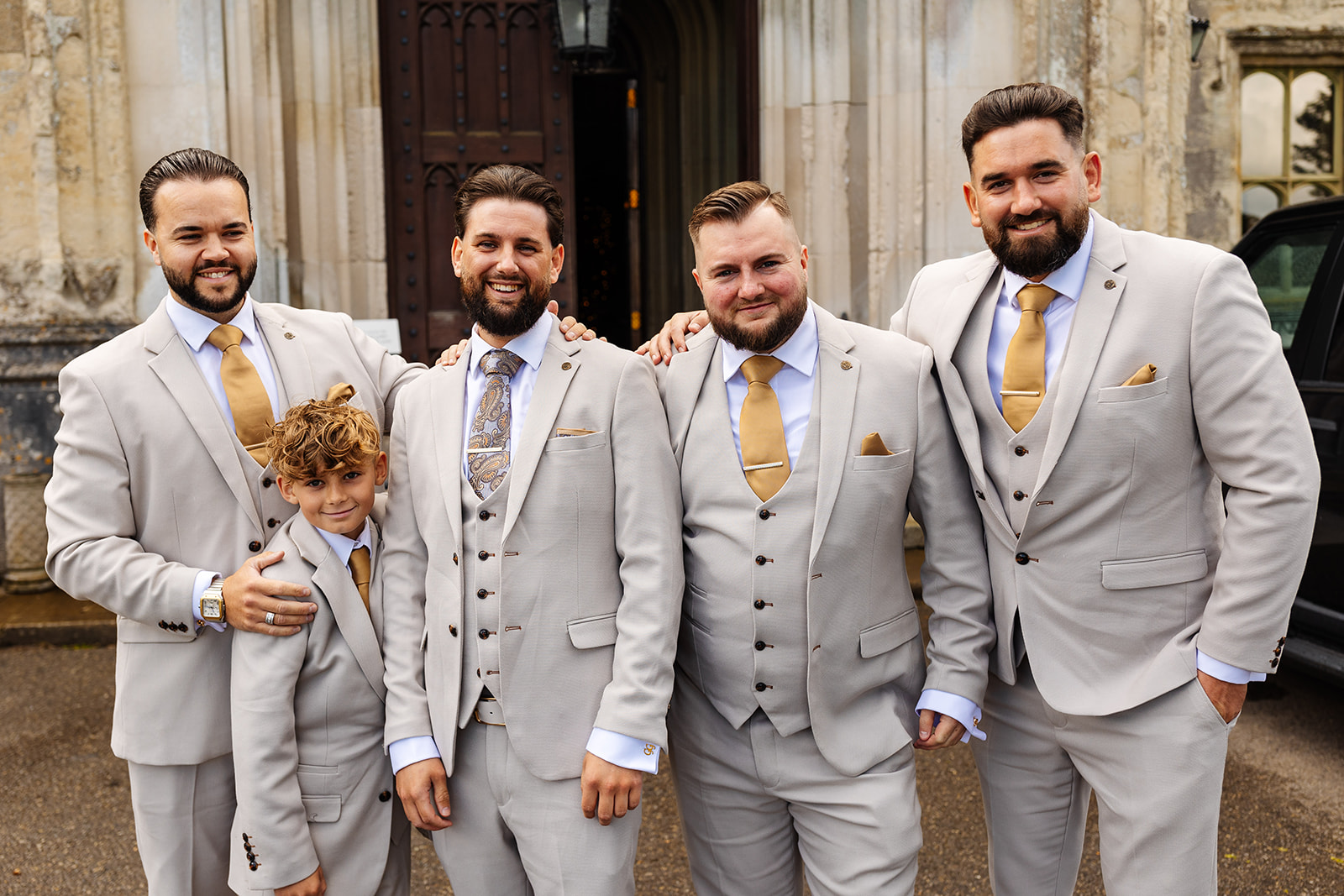 Groom with groomsmen outside Ashridge House, they are all in light beige suits with yellow ties and pocket sqaures 