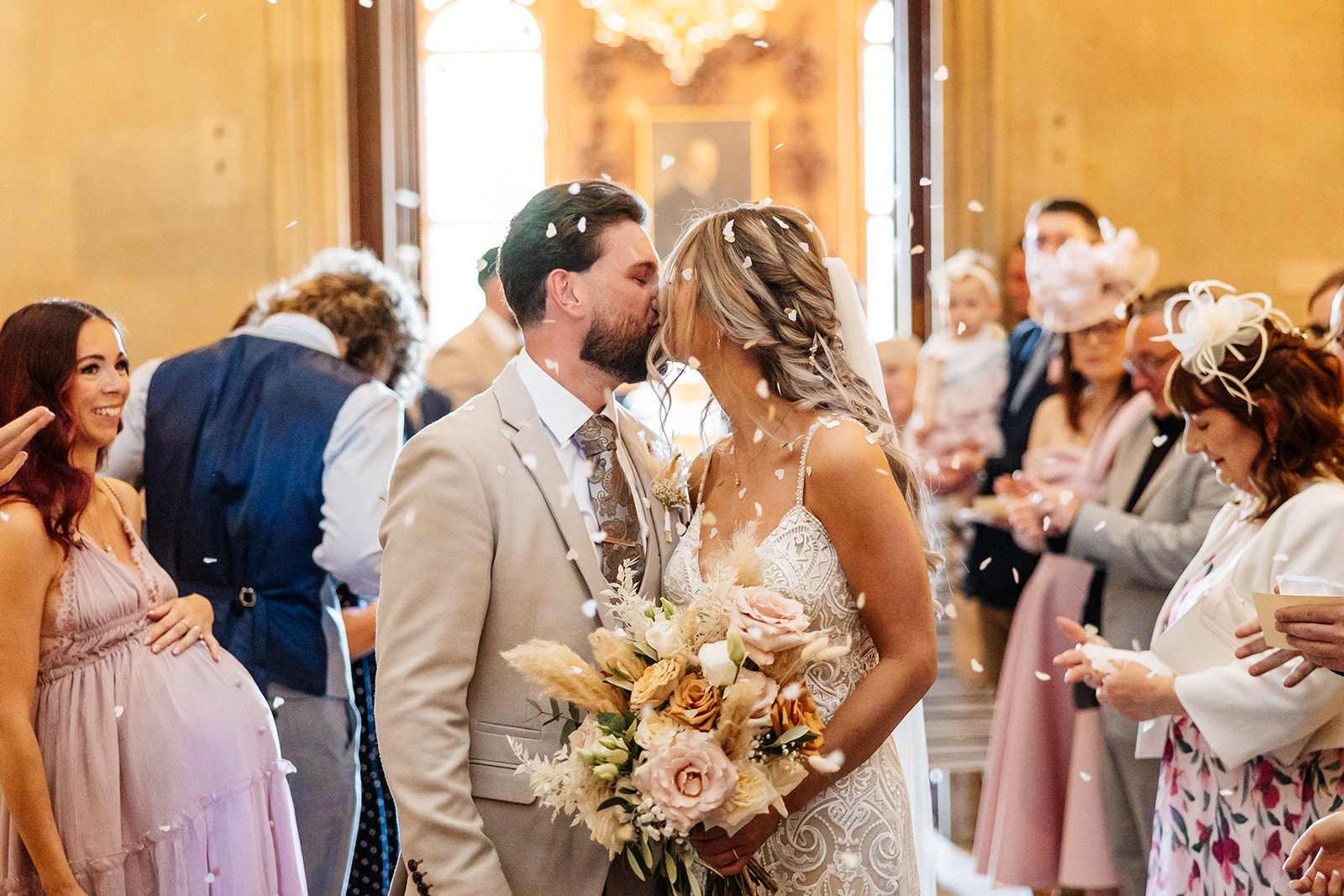 Couple share a kiss whilst confetti is thrown by guests after their ceremony 