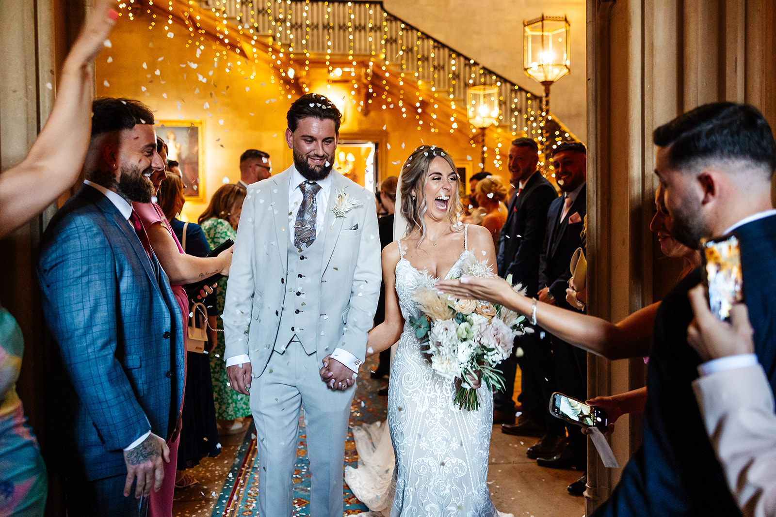Couple walk through confetti thrown by guests after their ceremony 