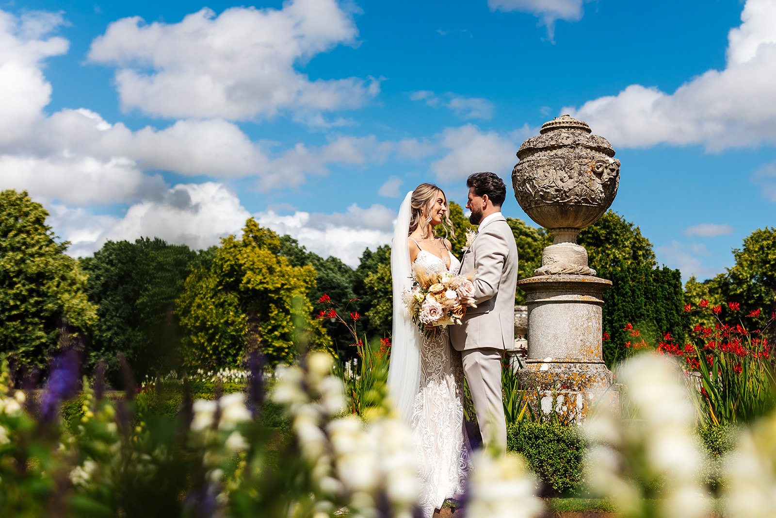 Bride & Groom in the grounds of Ashridge House, colourful flowers surround them