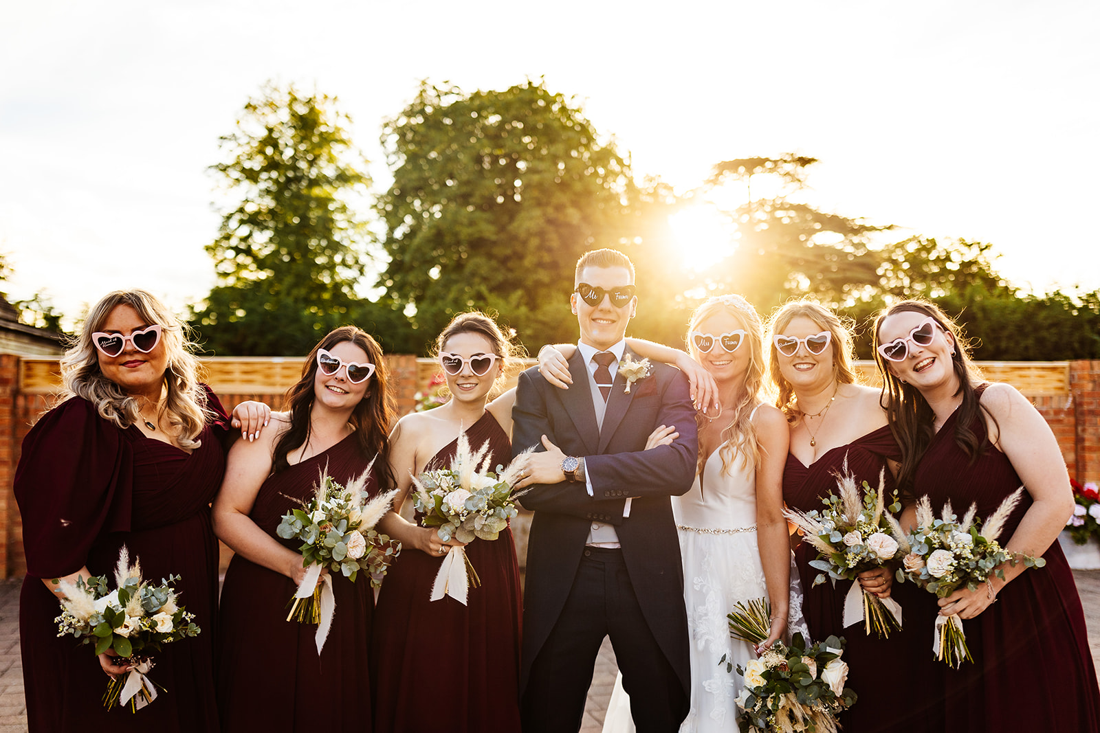 bridesmaids, bride and groom in low sun with heart shaped sunglasses at bassmead manor barns