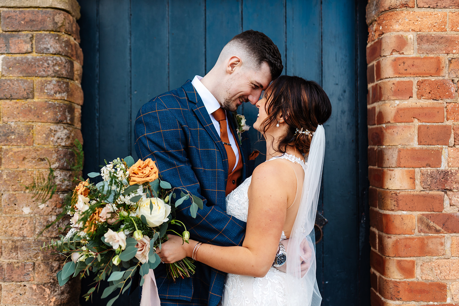 bride and groom in front of blue door at grangefields cripps wedding venue