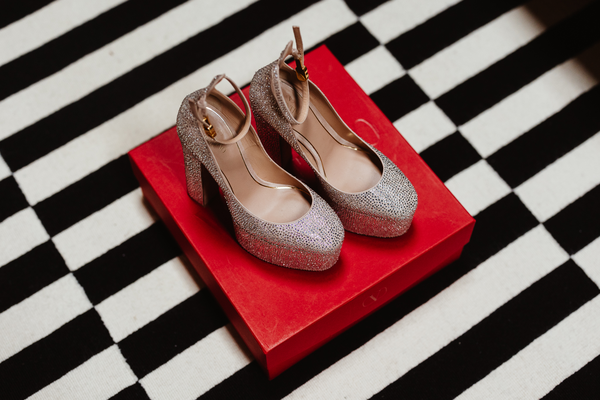 valentino platform glitter shoes sitting on top of a red box on a black and white rug