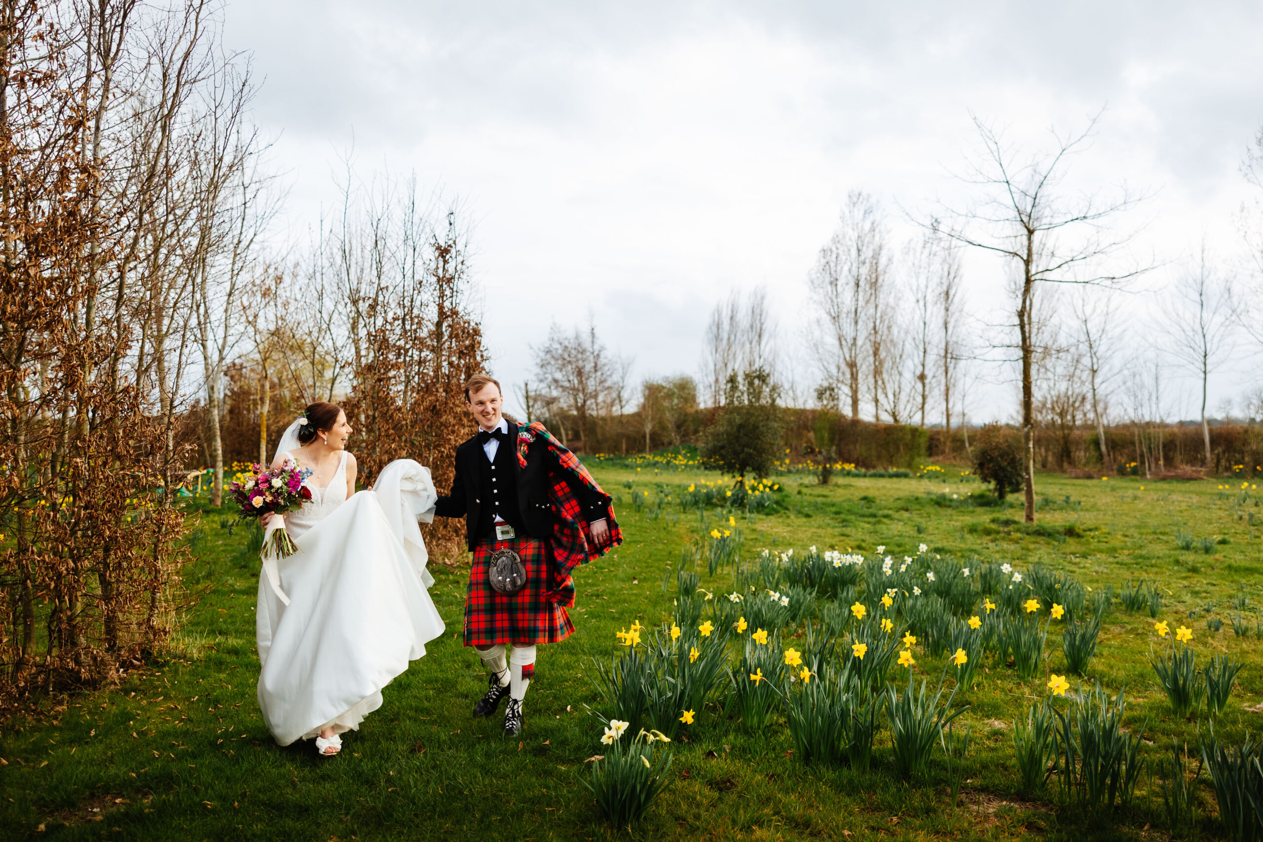 bride and groom amongst a meadow of daffodils at south farm