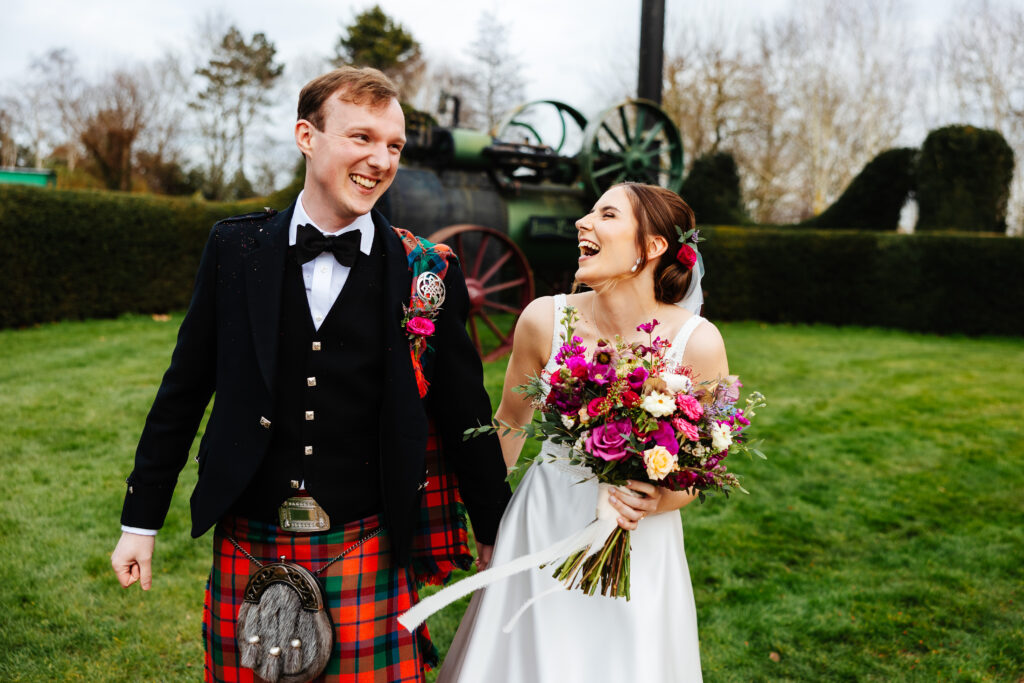 bride and groom in plaid and white wedding dress in front of vintage train at south farm wedding venue