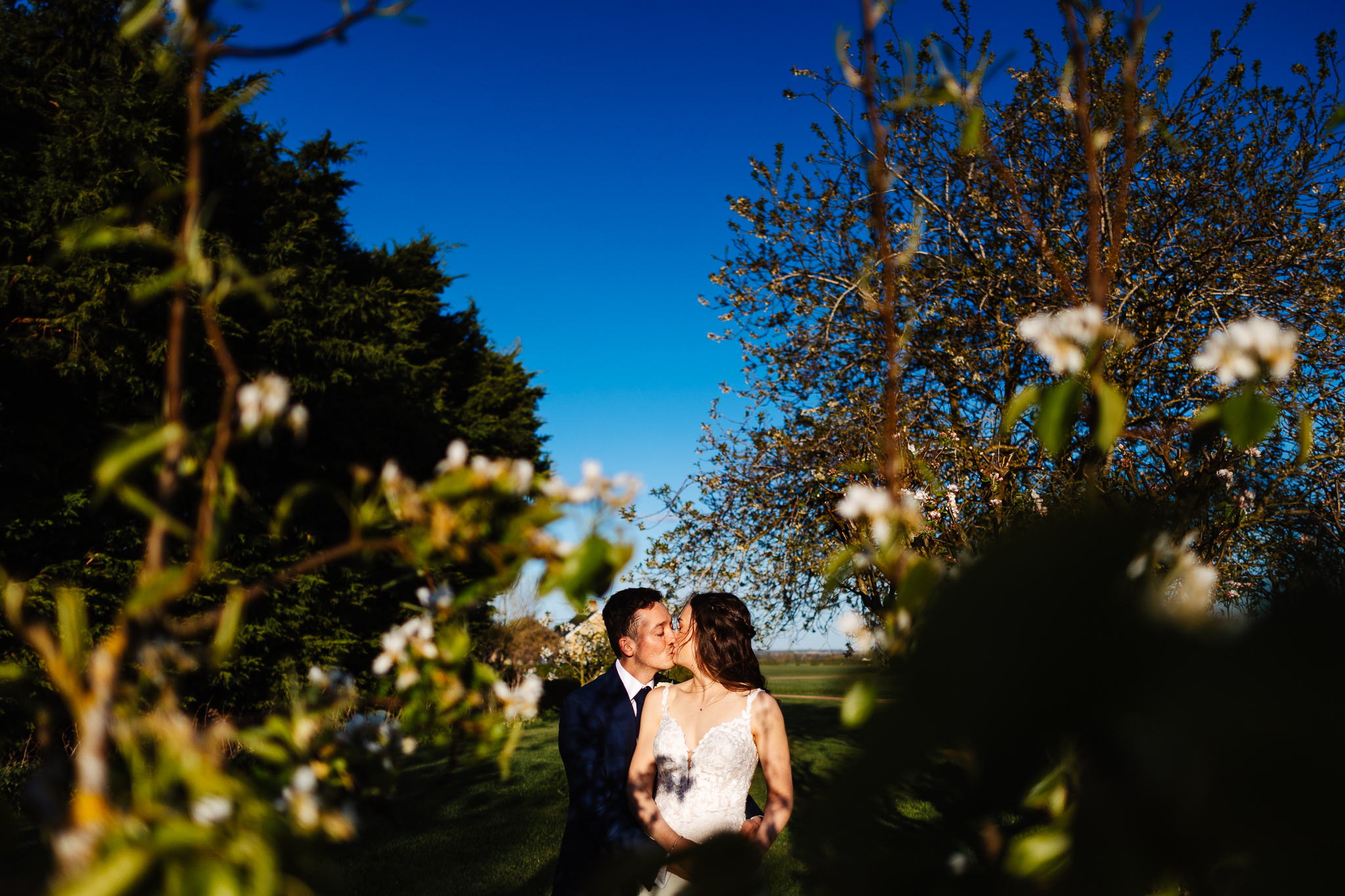 bride and groom kissing between pear trees at bassmead manor barns