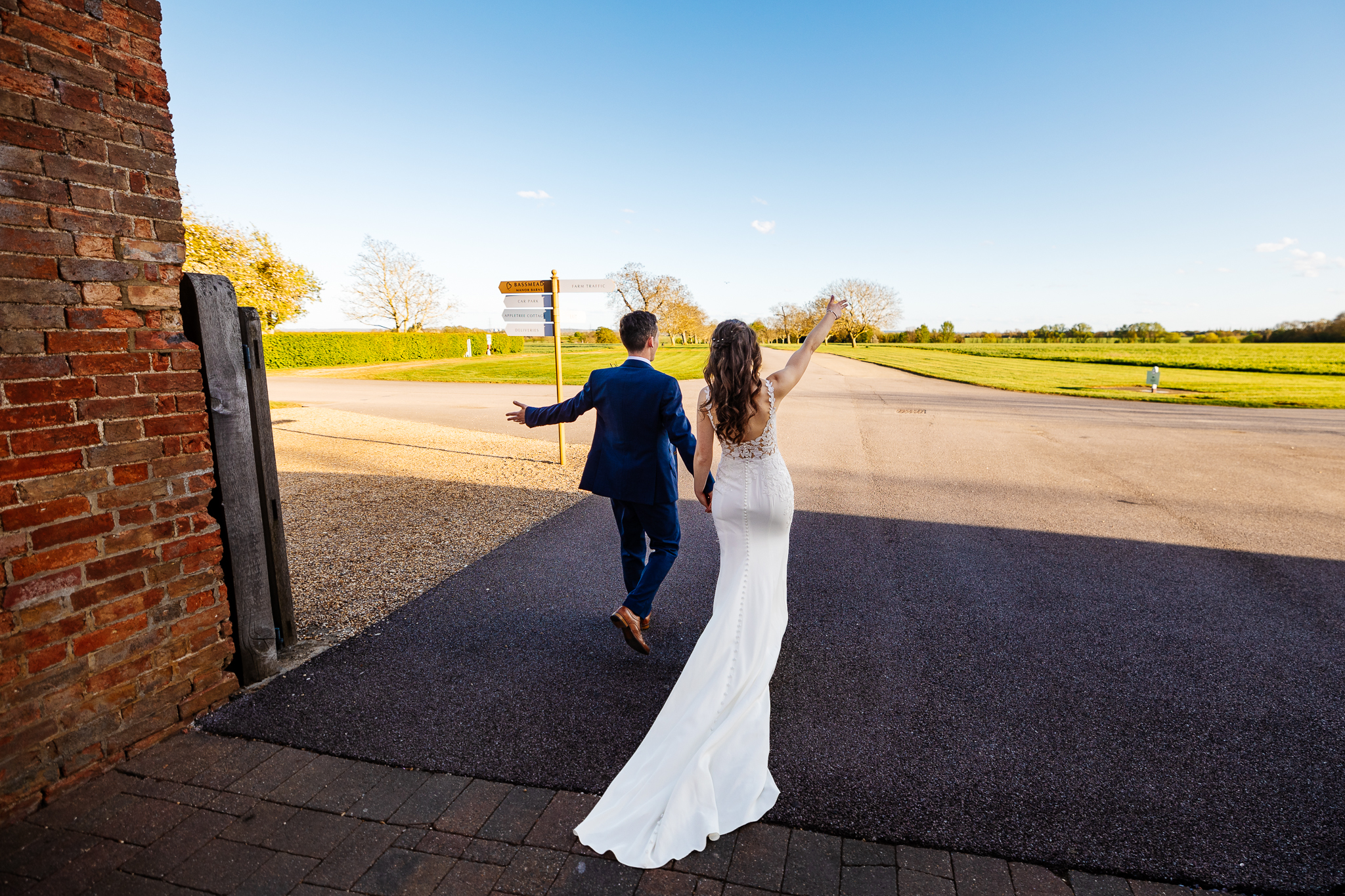 bride and groom running down the driveway of bassmead with their arms open